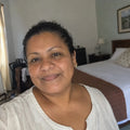 Retrato de una mujer salvadoreña de unos 50 años, dueña de un hostal, en una habitación con la cama tendida.